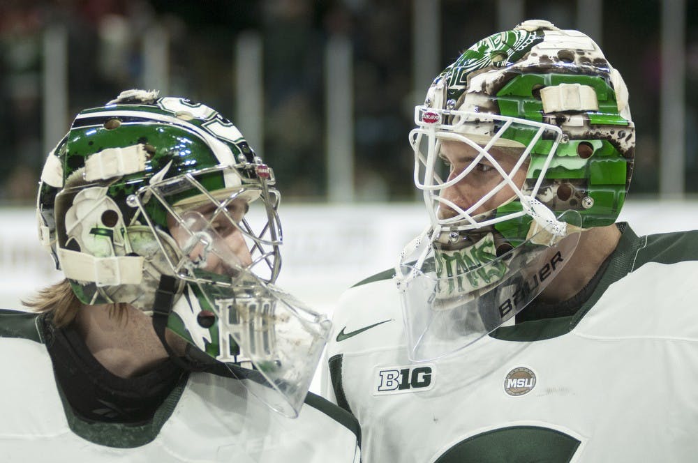 <p>Sophomore goaltender Jake Hildebrand, left, and senior goaltender Will Yanakeff skate off the ice following the first period of the game against Wisconsin on March 14, 2014, at Munn Ice Arena. The Spartans defeated the Badgers in overtime, 5-4. Danyelle Morrow/The State News</p>