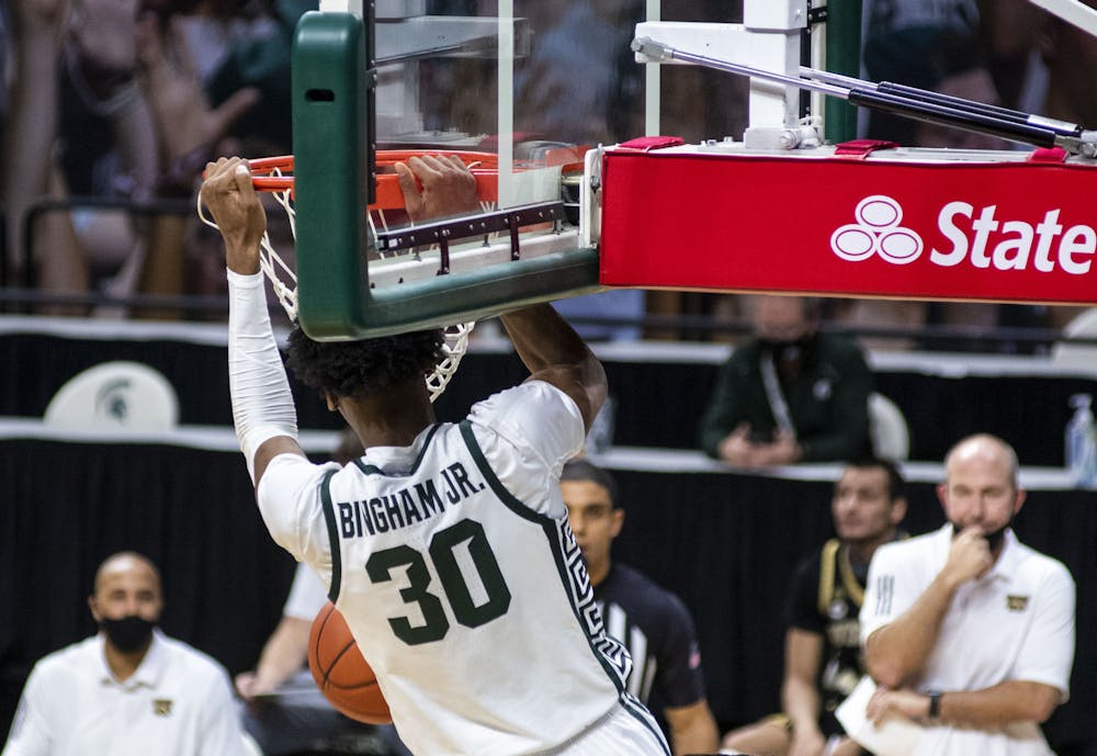<p>Junior forward Marcus Bingham Jr. (30) dunks the basketball against multiple Western Michigan players in the first half. The Spartans came back in the second half to win the game against the Broncos, 79-61, on Dec. 6, 2020.</p>