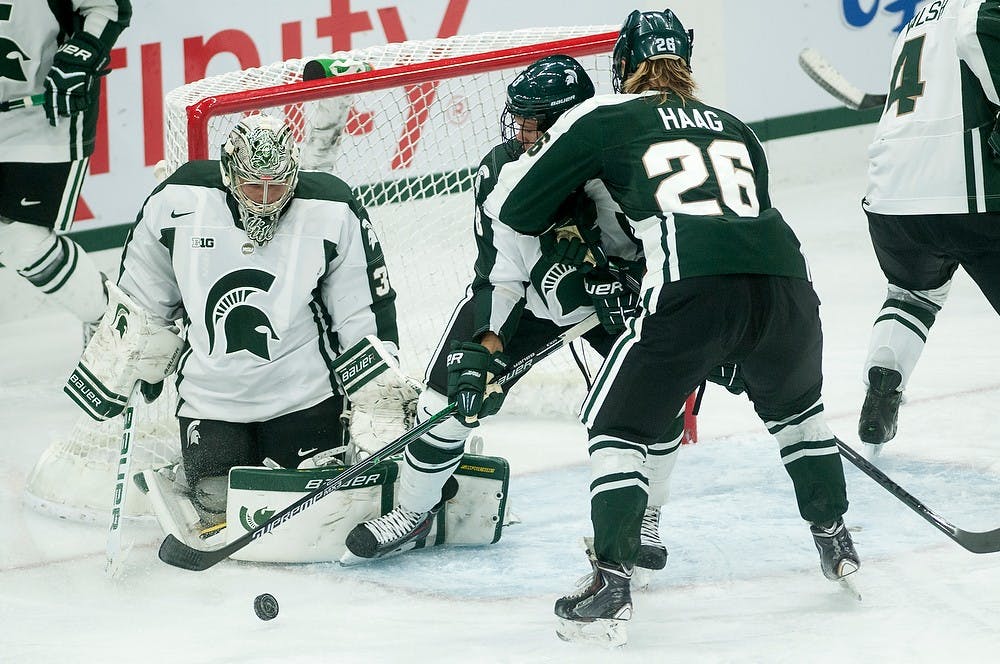 <p>Senior goalkeeper Zack Cisek and freshman defender Josh Jacobs try to hold off sophomore forward Villiam Haag on Oct. 5, 2014, at Munn Ice Arena during the Green and White game. Erin Hampton/The State News</p>