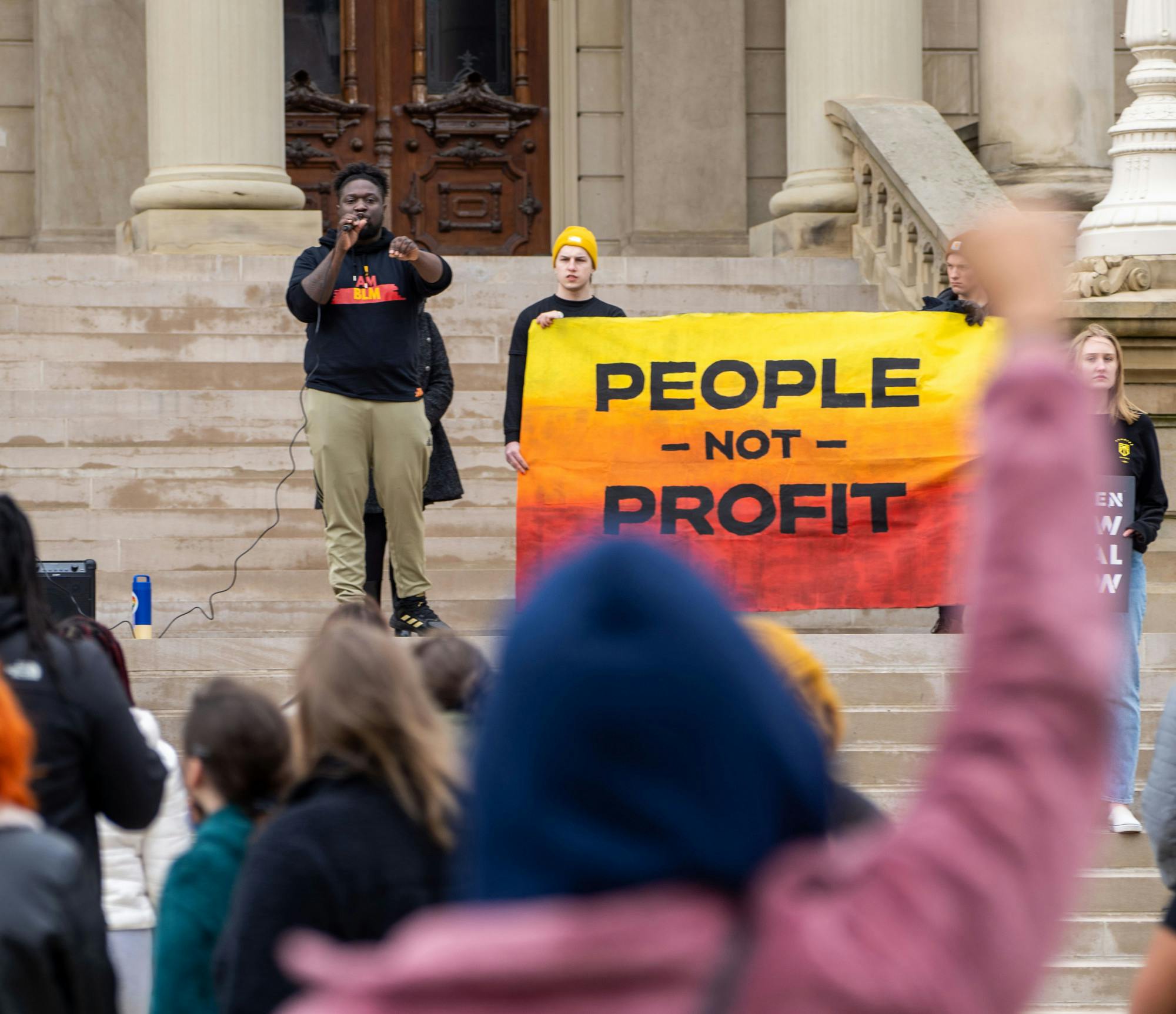 <p>A member of the crowd stands in solidarity with the speaker during the Friday for Futures Event in Lansing on March 25th, 2022.</p>