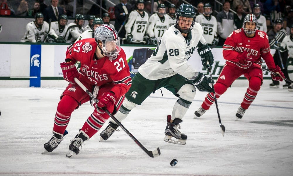 Senior right wing Villiam Haag (26) attempts to take the puck from Ohio State left wing Luke Stork (27) during the game against Ohio State on Feb. 17, 2017 at Munn Arena. The Spartans were defeated by the buckeyes, 3-2.