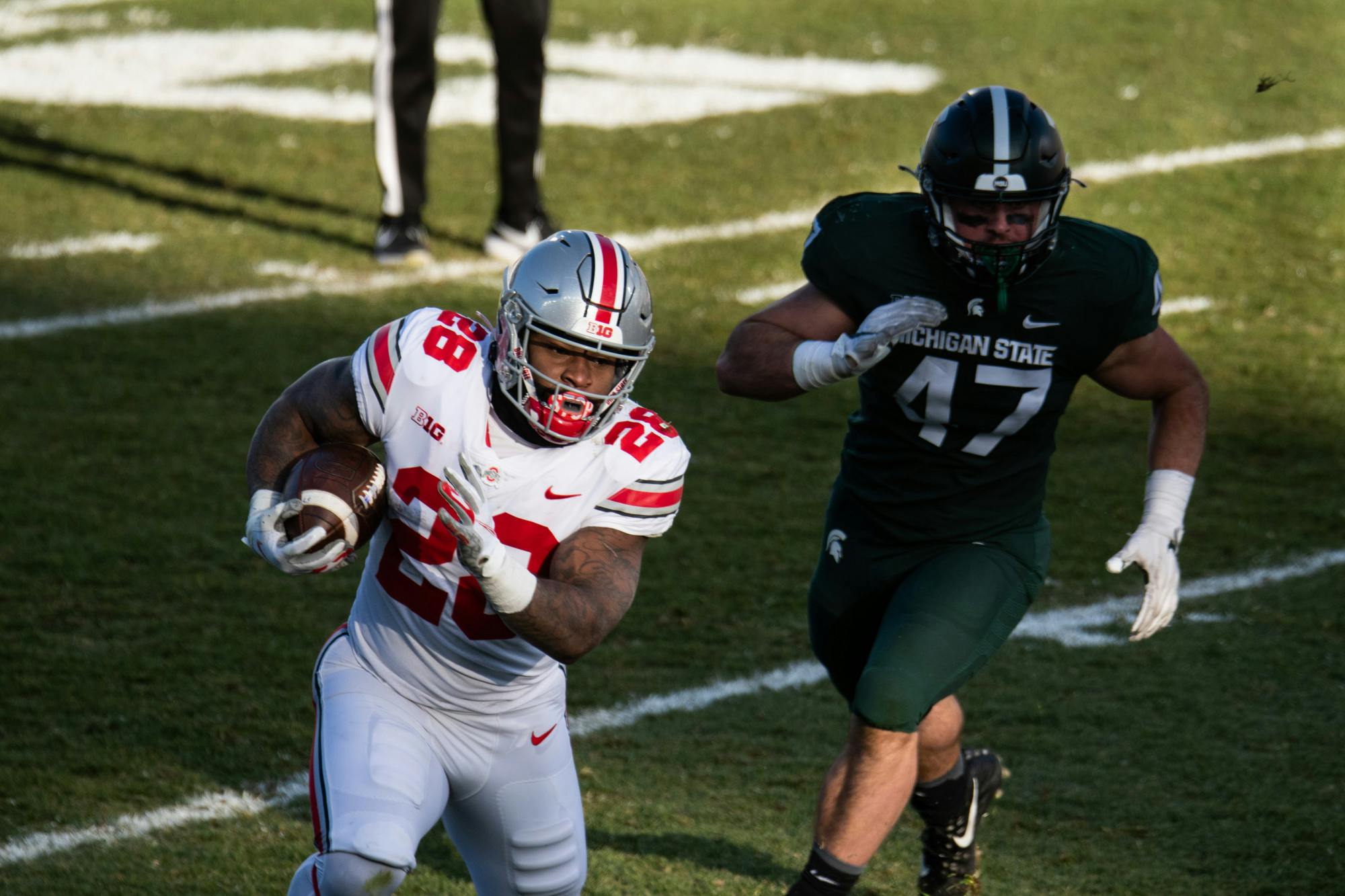 <p>OSU running back Miyan WIlliams (28) carries the ball, chased by MSU defensive end Jeff Pietrowski (47).</p>