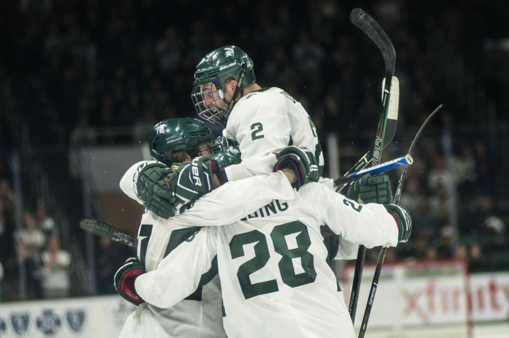 Sophomore defenseman Zach Osborn (2) celebrates with his teammates after scoring a goal on Nov. 4, 2016 at Munn Ice Arena. The Spartans defeated the Huskies in overtime, 3-2.
