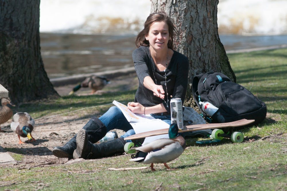 Business freshman Sara Condra feeds a duck on April 14, 2016 near the Red Cedar. 