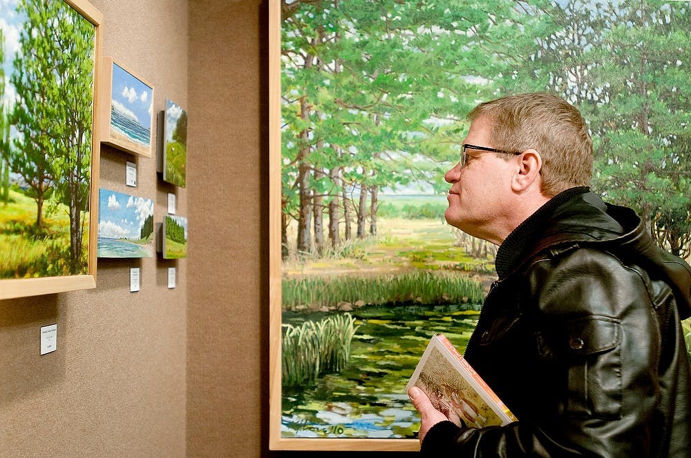 	<p>Danville, Mich., resident Kermit Johnson looks at &#8220;Paintings from Up North&#8221; on Feb. 22, 2013, at Mackerel Sky Gallery of Contemporary Craft. The collection is a series of landscapes by Michigan artist Kris Love. Julia Nagy/The State News</p>