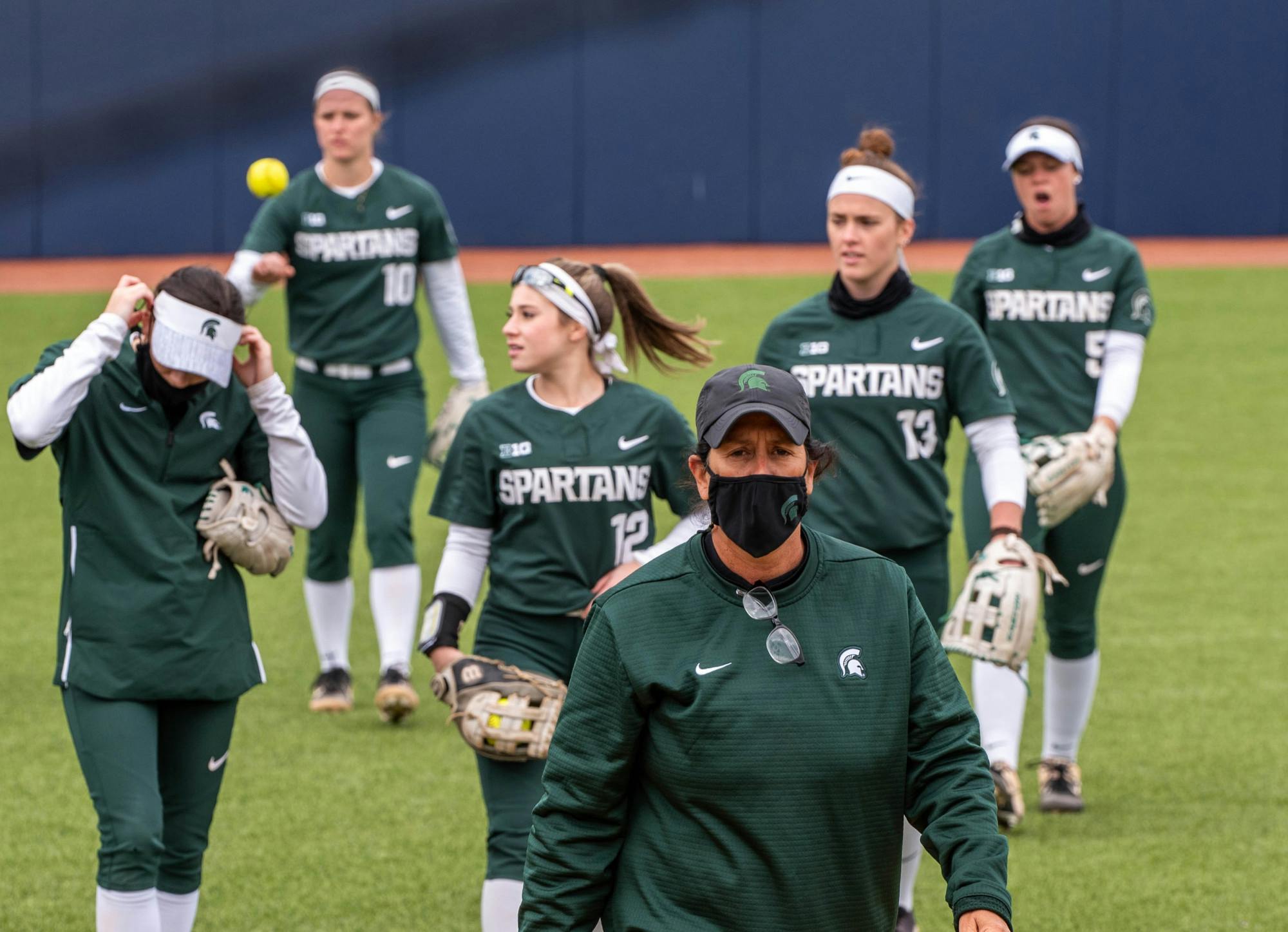 Coach Jacquie Joseph walks towards the dugout with her team behind her after a timeout. The Wolverines crushed the Spartans in a 6-1 win back on their home turf on April 14, 2021.