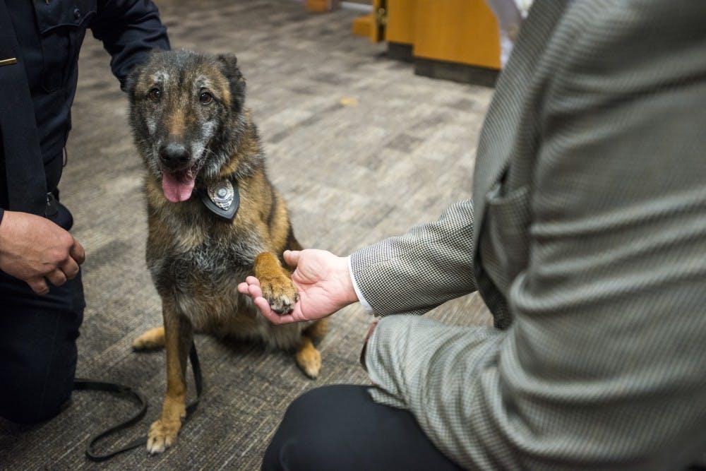 Tia shakes her paw with East Lansing City Manager George Lahanas after the K-9 retirement ceremony on Jan. 18, 2017 at the 54B District Court at 101 Linden St.