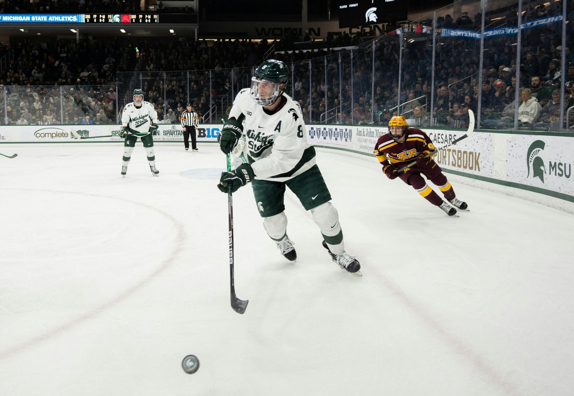 5th year defensemen Cole Krygier (8) keeps the puck away from University of Minnesota players during a game at Munn Ice Arena on Dec. 2, 2022. The Spartans lost to the Gophers with a score of 5-0. 