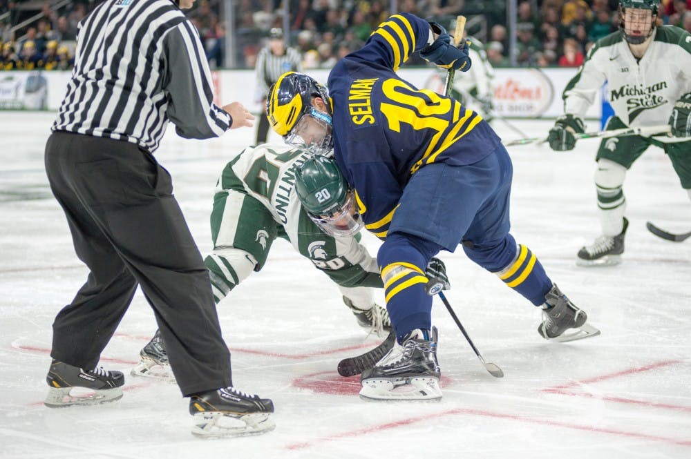 Senior forward Michael Ferrantino and Michigan forward Justin Selman fight for the puck during the puck drop during the hockey game against Michigan on Feb. 6, 2016 at Munn Ice Arena. The Spartans were defeated  by the Wolverines, 4-1.