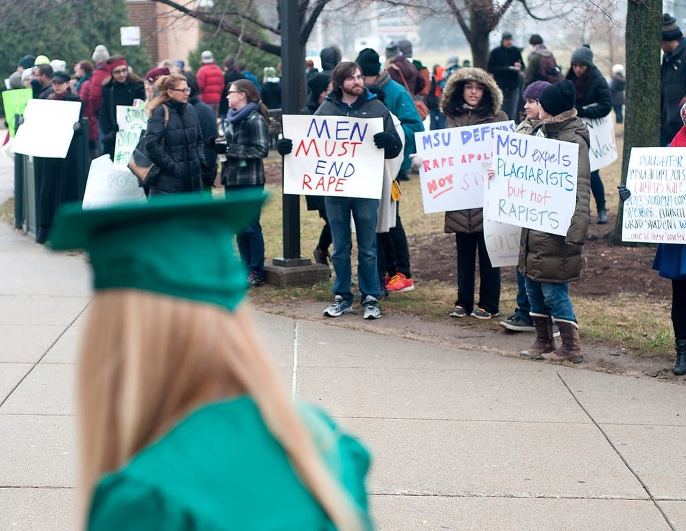 <p>A soon to be MSU graduate walks by protesters Dec. 13, 2014 during a protest against commencement speaker, George Will outside of Breslin Center. This protest was inspired by a column that Will had wrote earlier in the year. Jessalyn Tamez/The State News </p>