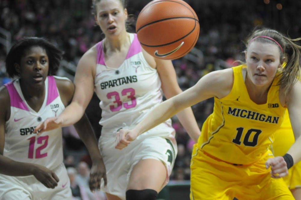 Michigan's junior guard Nicole Munger (10), sophomore forward Nia Hollie (12) and junior forward Jenna Allen (33) chase after the ball during the women's basketball game against Michigan on Feb. 11, 2018 at Breslin Center. The Spartans defeated the Wolverines, 66-61. (Annie Barker | The State News)