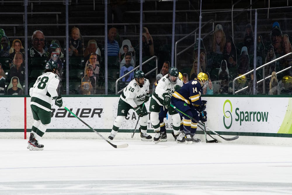 The Spartans pin Notre Dame in a corner in a scramble for the puck on Feb. 26, 2021.