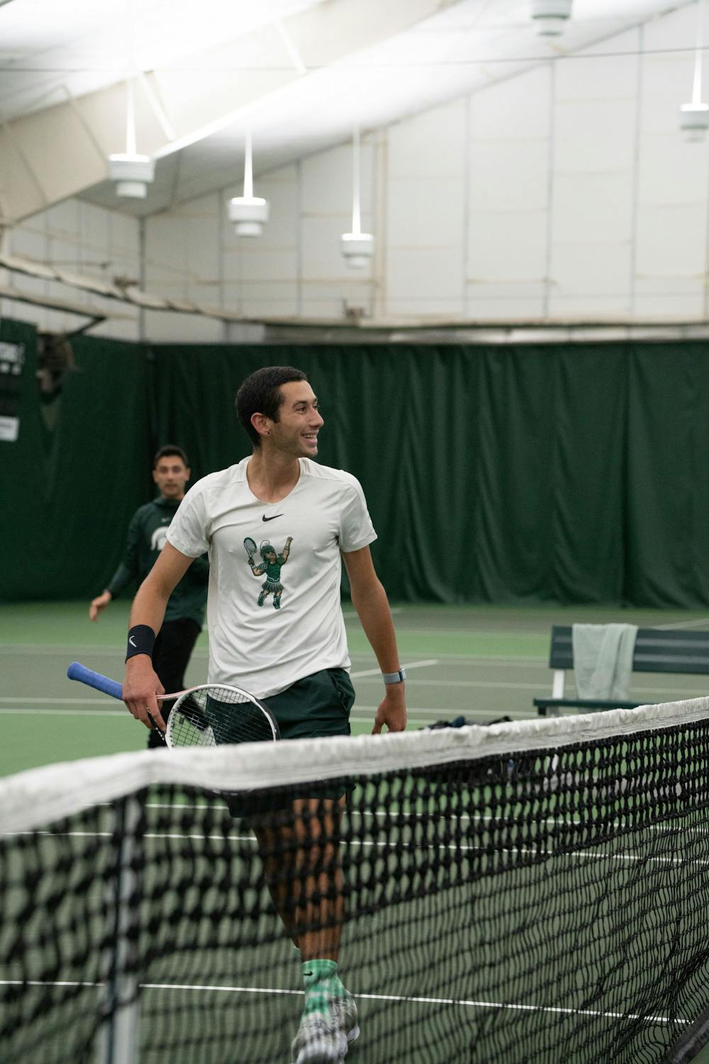 <p>Freshman Ozan Baris smiles after scoring a point against Michigan senior Ondrej Styler at the MSU Tennis Center on March 30, 2023. The Spartans lost to the Wolverines 6-1.</p>