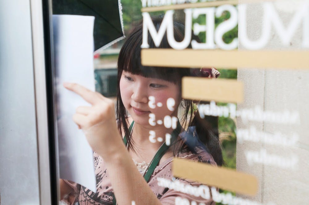 Shirayuri University student Shiori Murakami from Japan writes down the MSU Museum's hours during their scavenger hunt activity on Aug. 2, 2012. The students, who were a part of a three-week English language program, were tasked with writing information about landmarks around campus. Julia Nagy/The State News