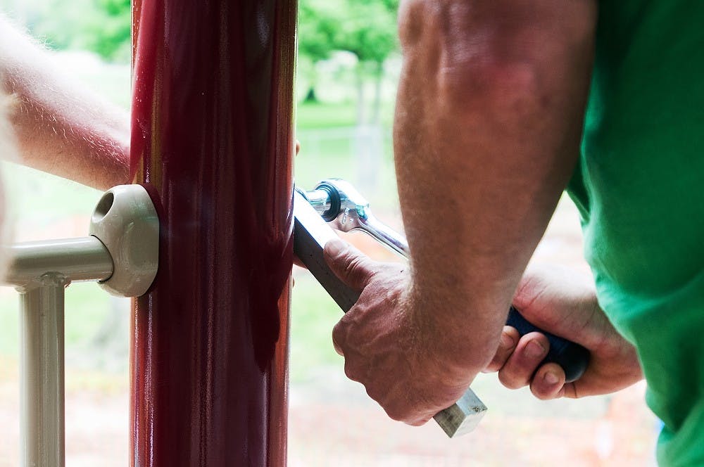 <p>Lansing resident Don Majkol, left, helps Zeeland, Mich., resident Brian Moulder, right, tighten bolts June 18, 2014, in Patriarche Park on the intersection of Alton Street and East Saginaw Highway in East Lansing. Majkol worked on the original constructions of Patriarche Park before the renovations. Corey Damocles/The State News</p>