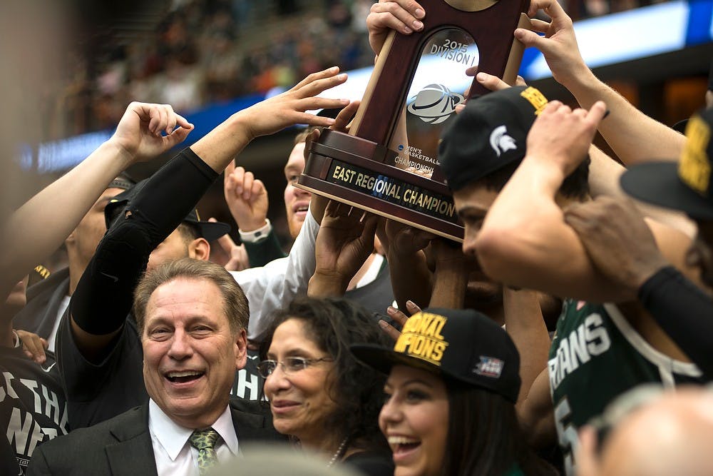 <p>Head coach Tom Izzo, his family and his team celebrate the win with the NCAA East Regional trophy March 29, 2015, during the East Regional round of the NCAA Tournament in the Elite Eight against Louisville at the Carrier Dome in Syracuse, New York. The Spartans defeated the Cardinals, 76-70. Erin Hampton/The State News</p>
