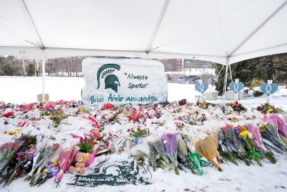 <p>Flowers and candles, covered in ice and snow, fill the ground alongside The Rock on Farm Lane on Feb. 17, 2023. The flowers have been collecting at The Rock in remembrance of the three students that lost their lives in the mass shooting on Feb. 13, 2023.</p>