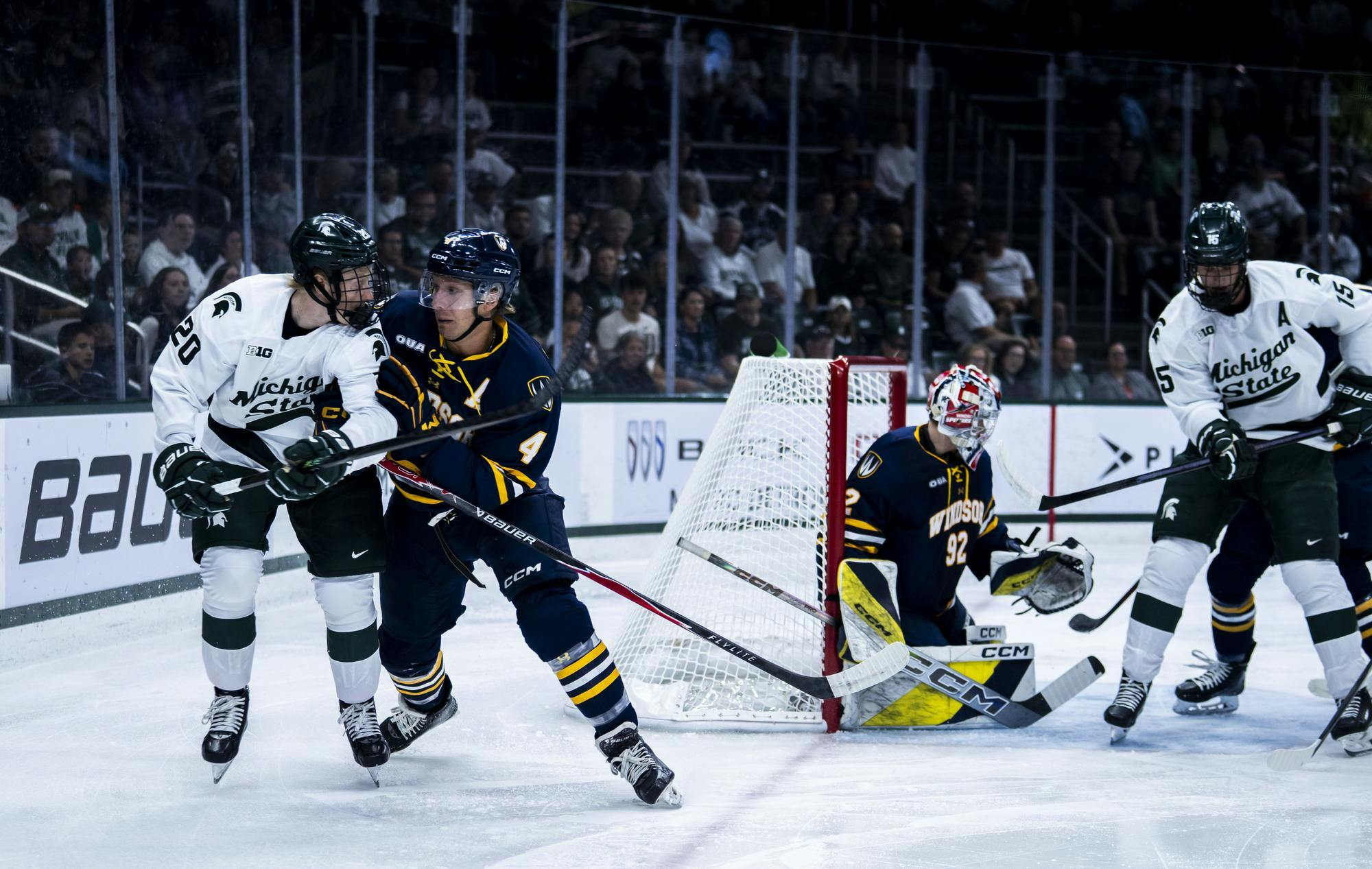 MSU senior forward Daniel Russell (20) and Windsor senior defense Stef Dobrich (4) race for the puck in the Munn Ice Arena on Oct. 3, 2025. 