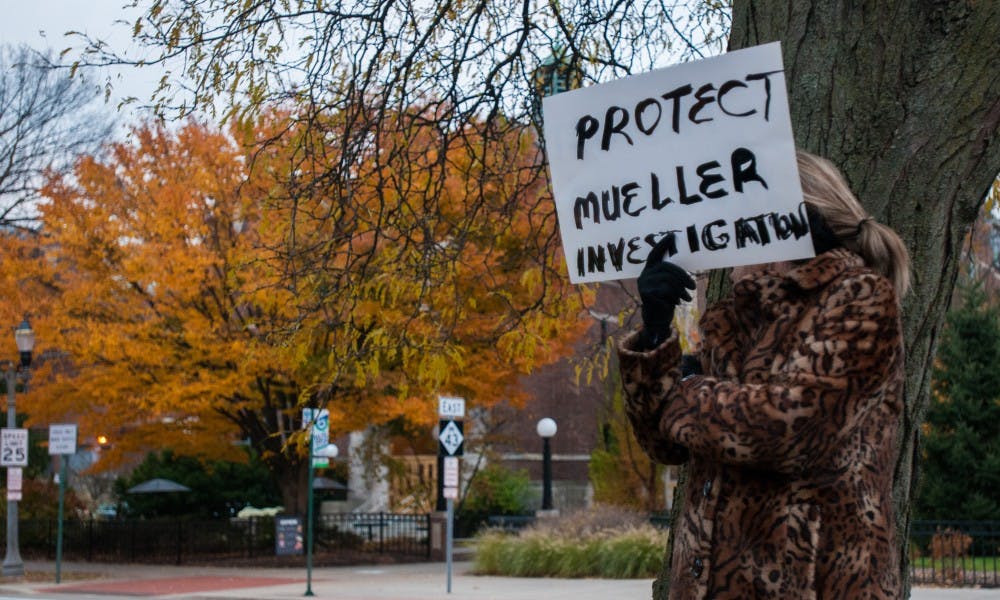 <p>A woman holds a sign during a "Trump is Not Above the Law" protest at Grand River Avenue and Abbot Road in East Lansing on Nov. 8, 2018.</p>