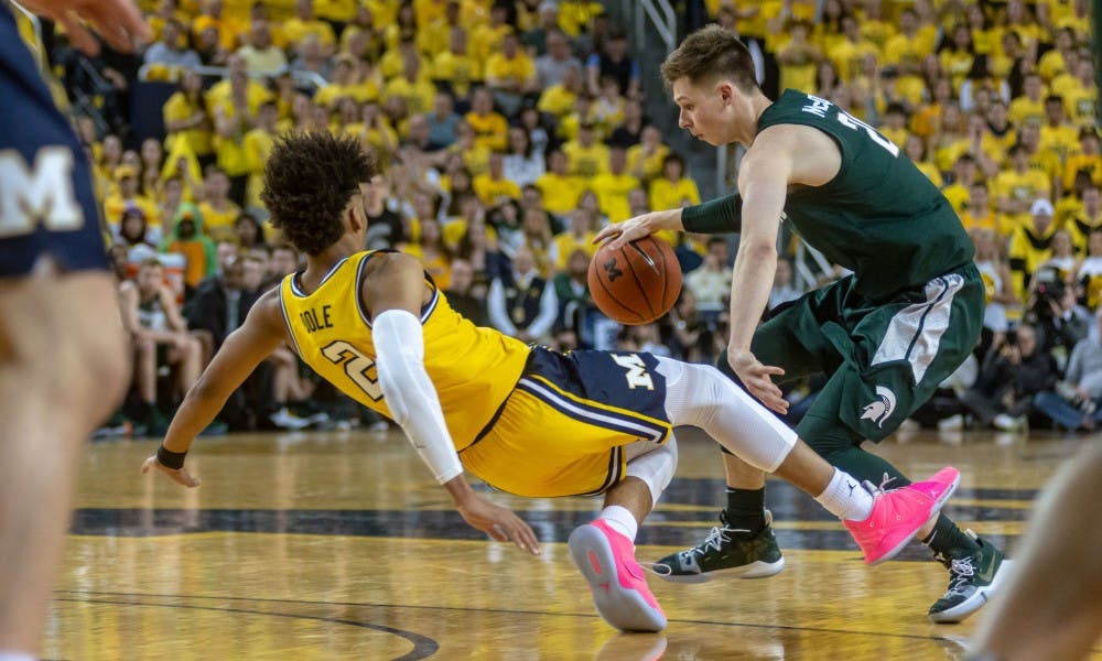 <p>Senior guard Matt McQuaid crosses over Michigan's Jordan Poole. The Spartans beat the Wolverines, 77-70, Feb. 24, 2019 at the Crisler Center.</p>