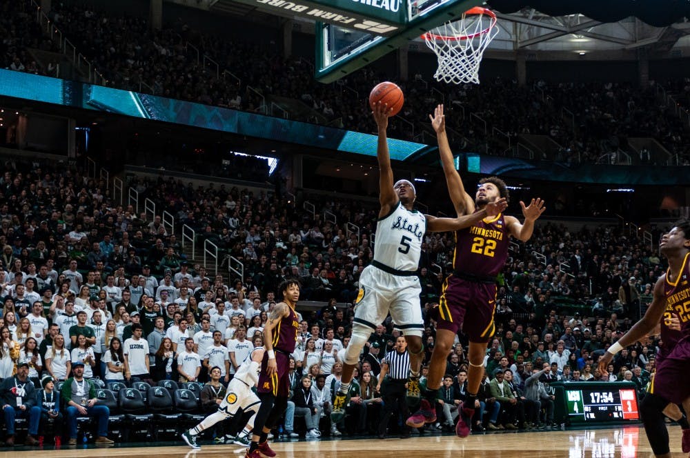 <p>Junior guard Cassius Winston (5) shoots a layup over Minnesota's Gabe Kalscheur at the Breslin Center on Feb. 9, 2019. MSU beat Minnesota 79-55 at the Breslin Center on Feb. 9, 2019.</p>