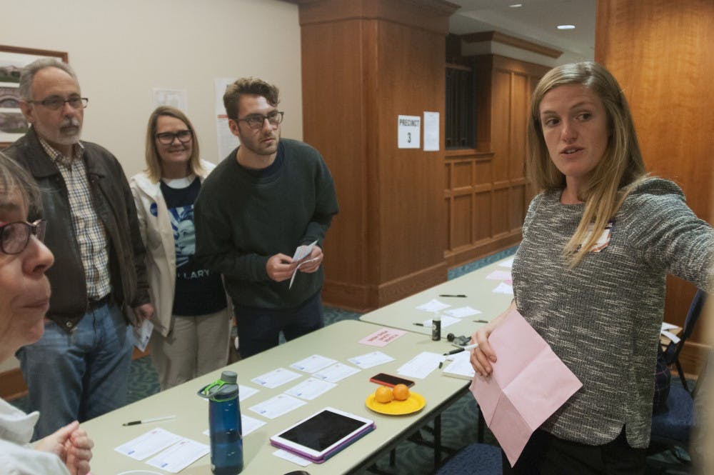 Lansing resident Emma Henry shows a family, including a first time voter, how to fill out a ballot on Nov. 8, 2016 in Hannah Community Center. Henry said it was her first time as an election official.