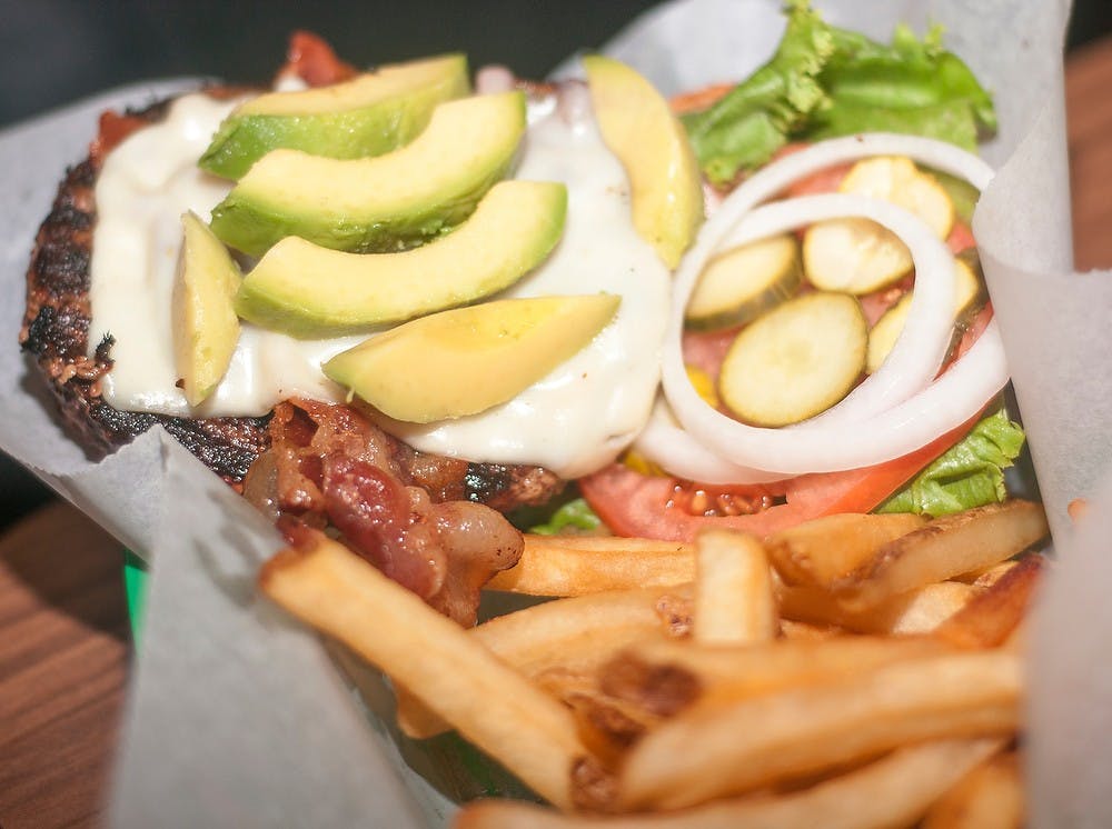 <p>A bacon avocado burger with fries is brought to a customer Sept. 3, 2014, at Crunchy's on W Grand River Avenue. Raymond Williams/The State News</p>