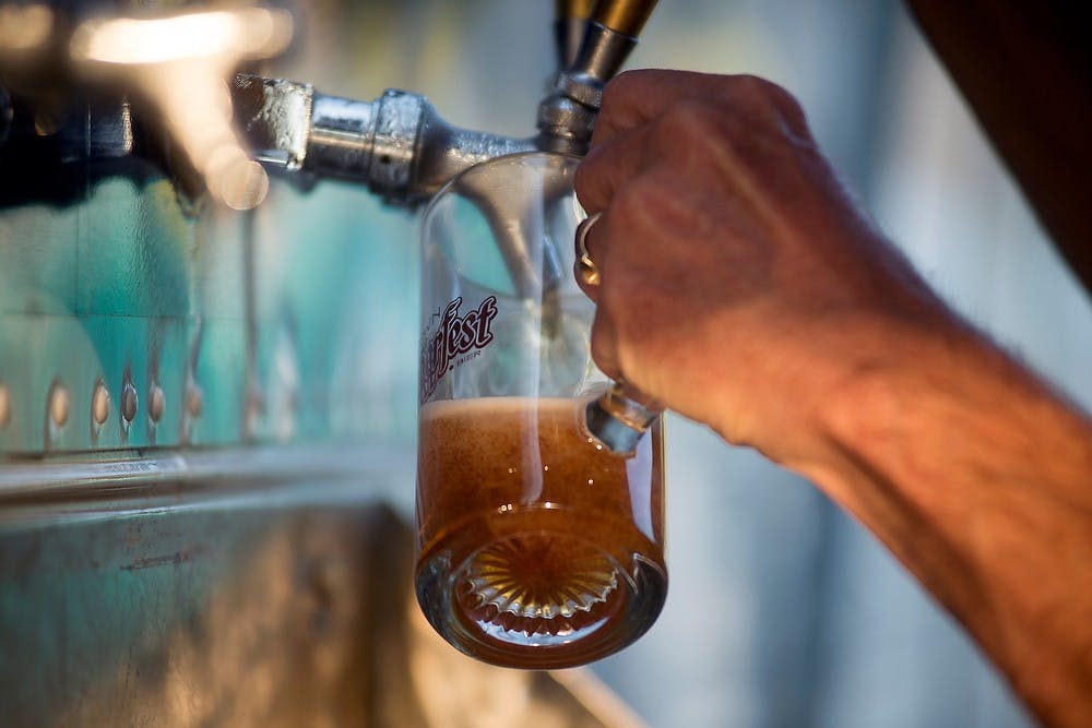 <p>Volunteer Tom Wellman pours a glass of beer Oct. 4, 2013, during Old Town Lansing Oktoberfest. A variety of beers and hard ciders were served at the event. Julia Nagy/The State News</p>