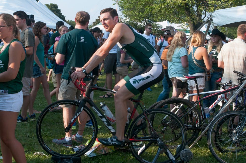 <p>Packaging senior David Shuler rides his bike during Sparticipation on Sept. 1, 2015, at Cherry Lane Field. Shuler is a member of Michigan State Triathlon.&nbsp;</p>