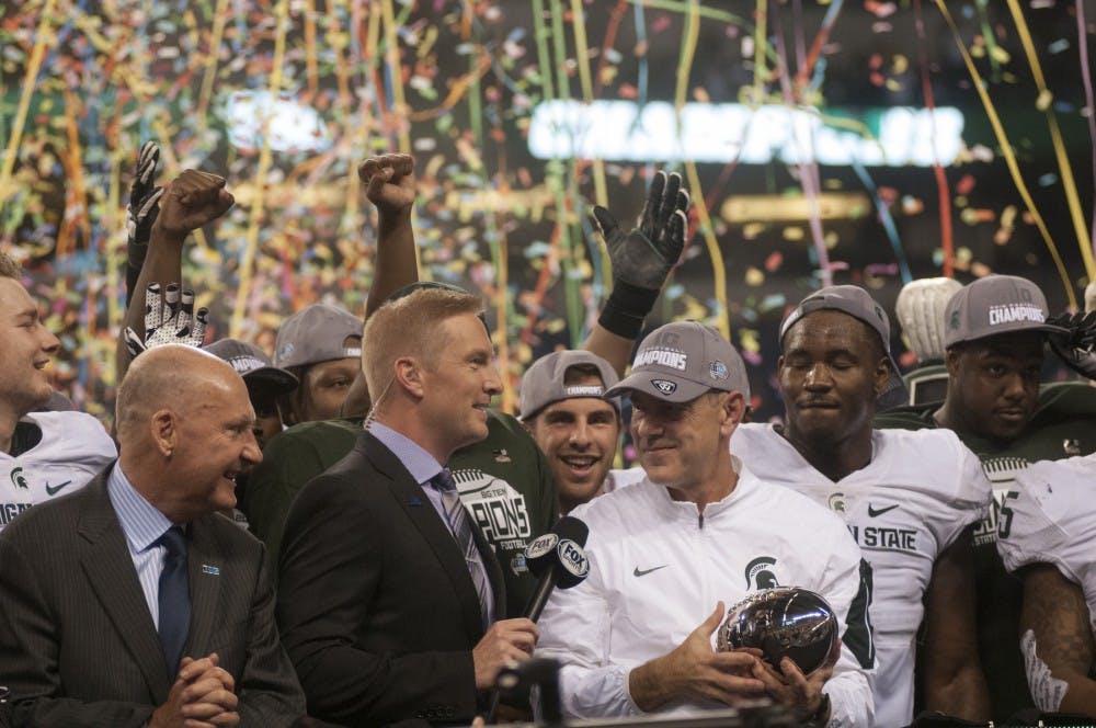 Head coach Mark Dantonio is presented with the trophy on Dec. 5, 2015 after the Big Ten championship game against Iowa at Lucas Oil Stadium in Indianapolis. The Spartans defeated the Hawkeyes, 16-13.