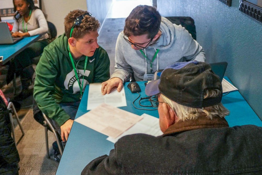 Accounting junior Matthew Sheehan, left, and accounting junior Quinton Slusser, right, help an East Lansing native who asked to remain anonymous with his taxes during a VITA event on March 13, 2017 at East Lansing VITA Super Center (Deer Path Site) at 1290 Deer Path Ln. in East Lansing. The club consists of over 100 student volunteers who are trained to help low-income individuals, students and families with their taxes free of charge.