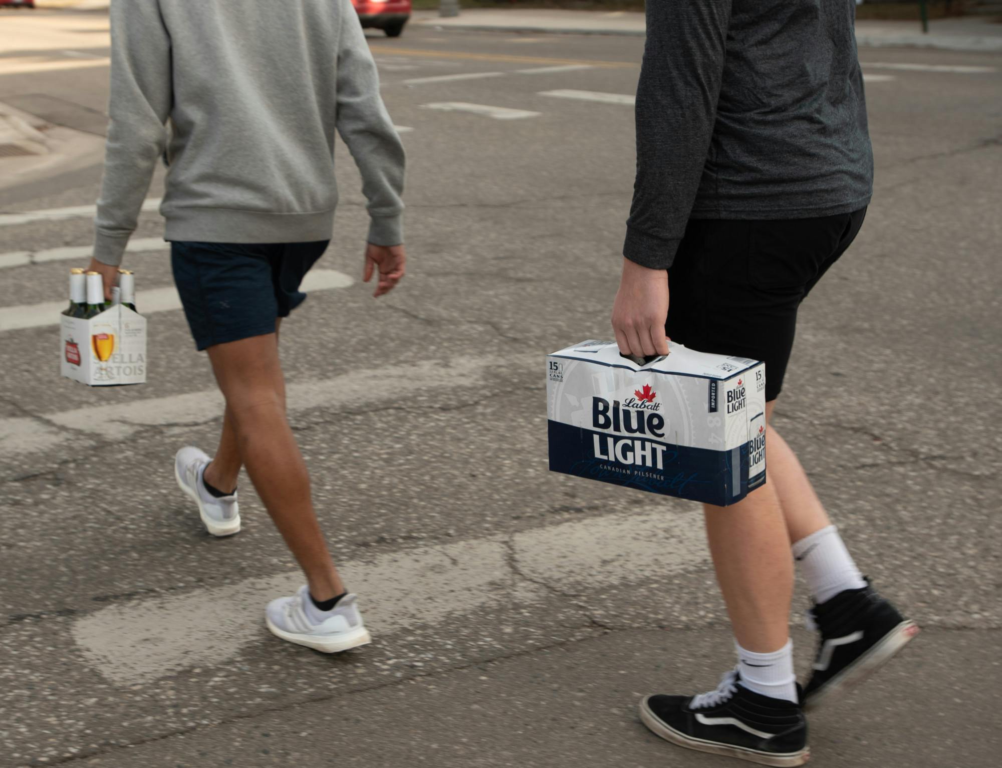 Two people carry alcohol towards a yard full of people drinking on March 13, 2021.