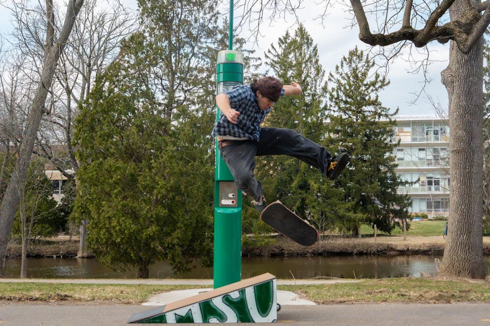 Augustine Alafita, vice president of MSU Skate Club, performs a trick during skate club outside of Shaw Hall on Michigan State University’s campus in East Lansing, Mich., on March 20, 2026.