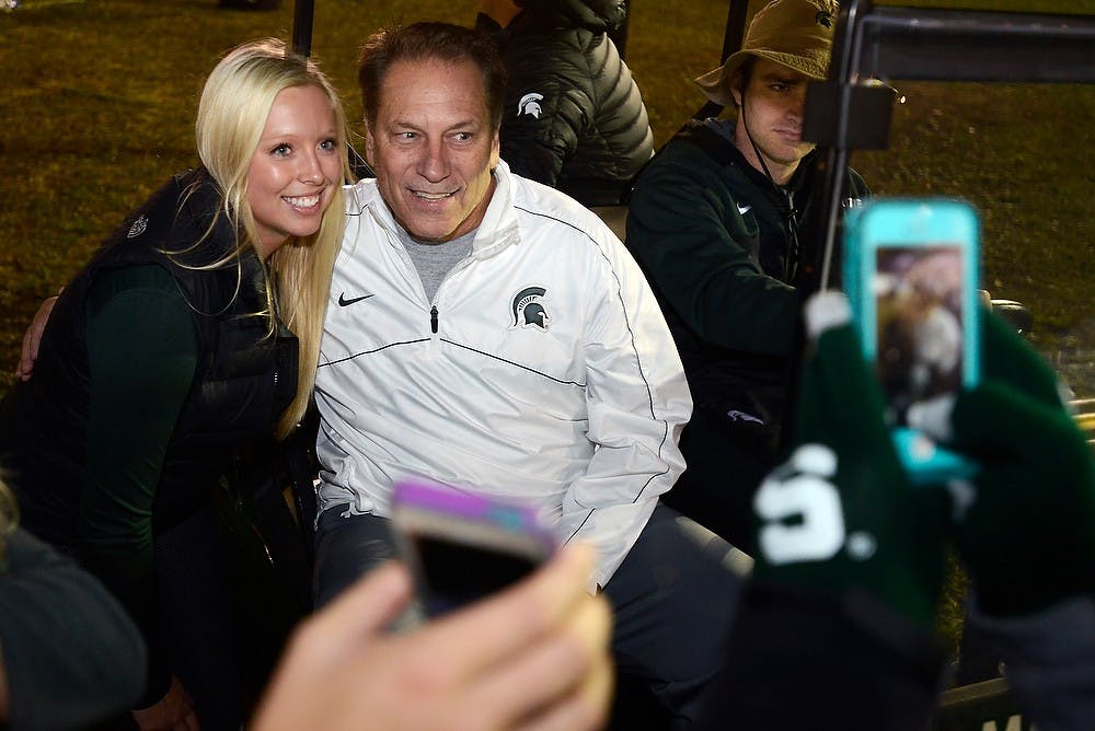 <p>Pre-nursing sophomore Kathryn Hedenquist takes a photo with men's basketball head coach Tom Izzo on Oct. 17, 2014, during the Izzone Campout at Munn Field. Hundreds of students battled the cold and rain to sleep outdoors overnight in hopes of getting lower bowl seating. Julia Nagy/The State News</p>