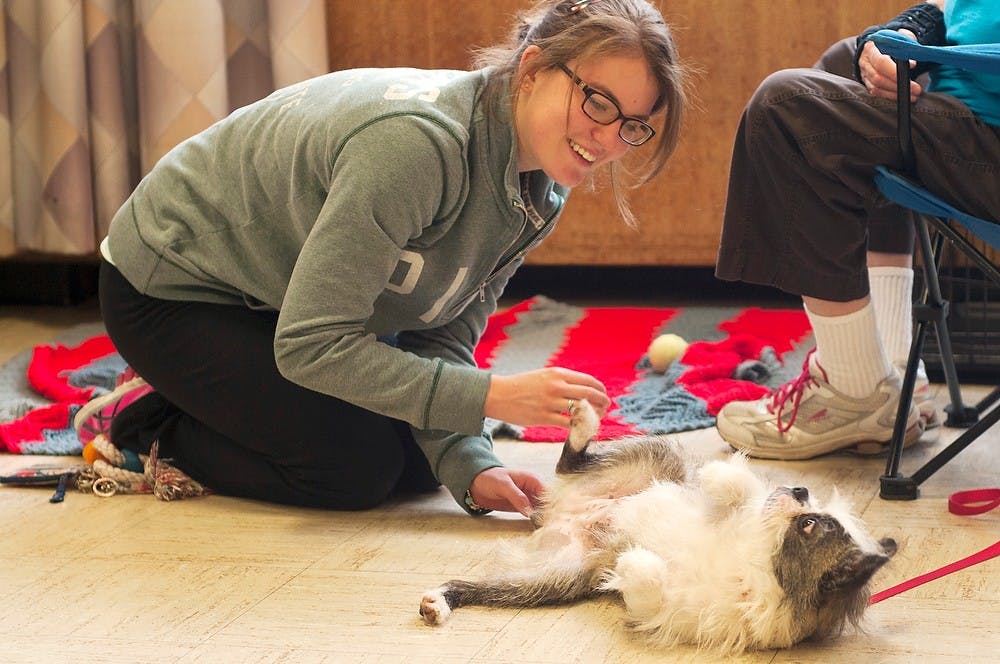 <p>No preference engineering freshman Megan Friedrich plays with a dog named Sushi on Dec. 5, 2013, at Shaw Hall. Students were invited to come rent play time with dogs from the Capital Area Humane Society-Lansing to help relieve stress before finals. Margaux Forster/The State News</p>