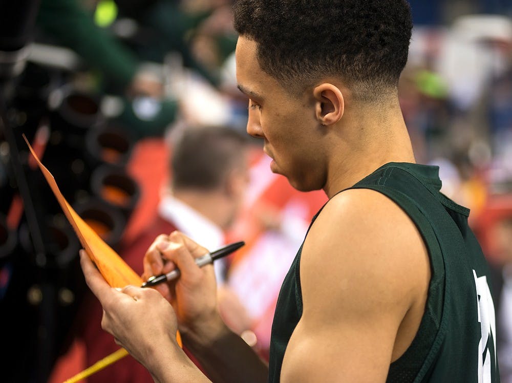<p>Senior guard Travis Trice signs an autograph April 3, 2015, during a practice at the NCAA Tournament in the Final Four round at Lucas Oil Stadium in Indianapolis, Indiana. The Spartans practiced in preparation to play against Duke the next day. Erin Hampton/The State News</p>