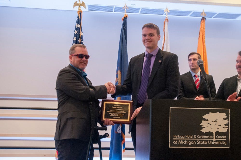 Keynote speaker David Denhardt is handed an award during the Veterans Breakfast on Nov. 11, 2016 at Kellogg Center.  