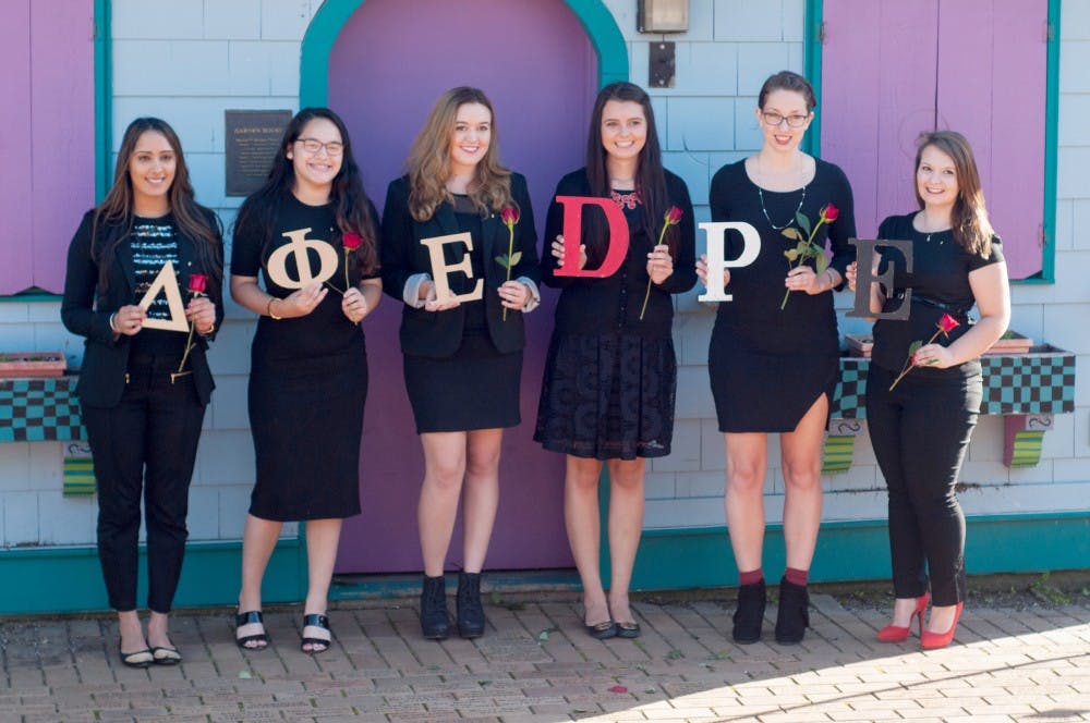 <p>From left to right, economics junior Priya Jaswal, political science junior Maisie Rodriguez, international relations junior Katie Patterson, international relations junior Allecia Jurkiewicz, comparative culture and politics senior Heather Harmon and international relations junior Jesse Endert hold up letters during the Delta Phi Epsilon initiation on Sept. 13, 2015, at the MSU Michigan 4-H Children's Garden.</p>