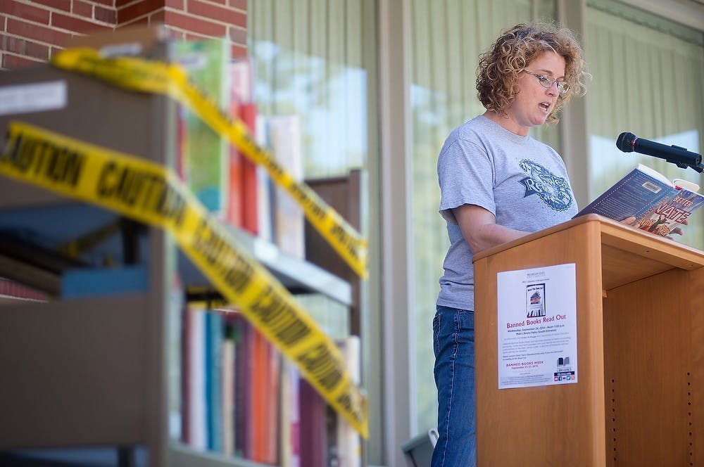 <p>Doctoral student Kristin McIlhagga reads a passage from "Better Nate Than Ever" by Tim Federle during a banned books reading Sept. 24, 2014, at the Main Library. Attendees could bring books with them or choose from books on racks wrapped with caution tape. Julia Nagy/The State News</p>