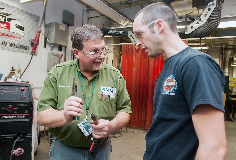 	<p>Mechanical engineering senior Colin Perrault, right, talks with Engineering Technician Roy Bailiff on Thursday, Dec. 6, 2012, in the Engineering Building. Perrault was working on a switch box for his team&#8217;s project for Design Day. Julia Nagy/The State News</p>