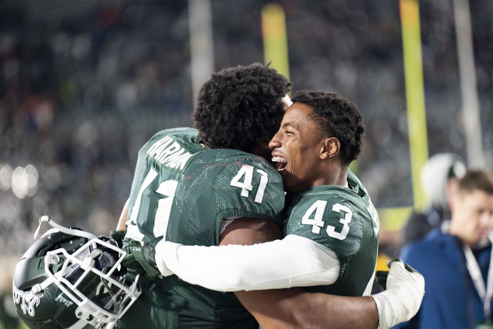 Redshirt freshman defensive tackle Derrick Harmon (41) and freshman safety Malik Spencer (43) embrace after winning the game against Wisconsin on October 15, 2022. The Spartans beat the Badgers 34 to 28. 