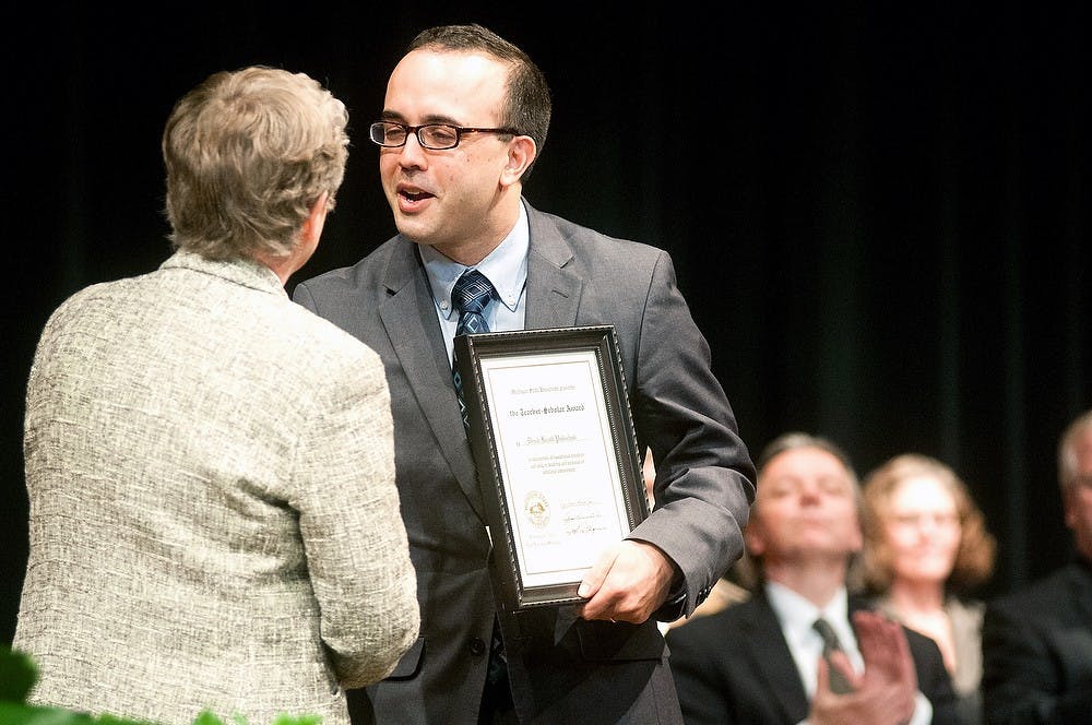 	<p><span class="caps">MSU</span> President Lou Anna K. Simon presents College of Music professor Derek Polischuk a Teacher-Scholar award Feb. 12, 2013, at the Pasant Theatre. The Teacher-Scholar awards were given to six faculty members who have shown scholarly promise. </p>