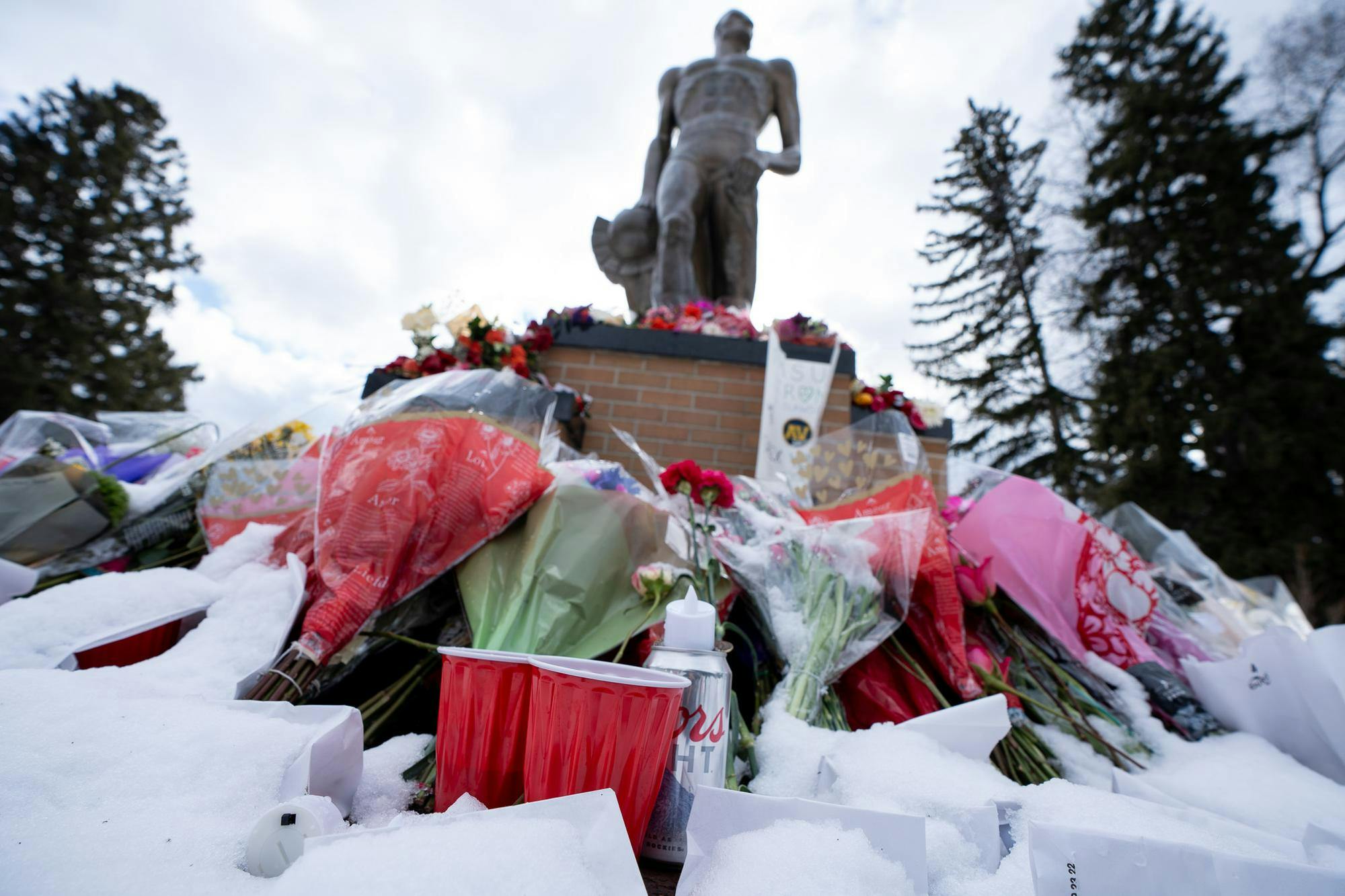 The Phi Delta Theta Fraternity laid beer, Red Solo Cups and the fraternity coin in honor of their fraternity brother Brian Fraser, who died in MSU’s mass shooting on Feb. 13, 2023. The beer, cups and coin were among flowers, messages and luminaries that were laid out the night of the one year anniversary of the shooting on Feb. 13, 2024. Photograph taken on Feb. 15, 2024. 