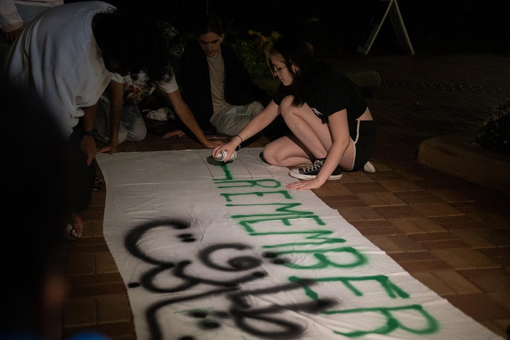 Graphic design freshman Grace Ferow sprays the Palestinian flag onto a banner at an anniversary memorial for Michigan State Humphrey fellow and Israeli bombing victim Tariq Thabet on Oct. 30, 2024.