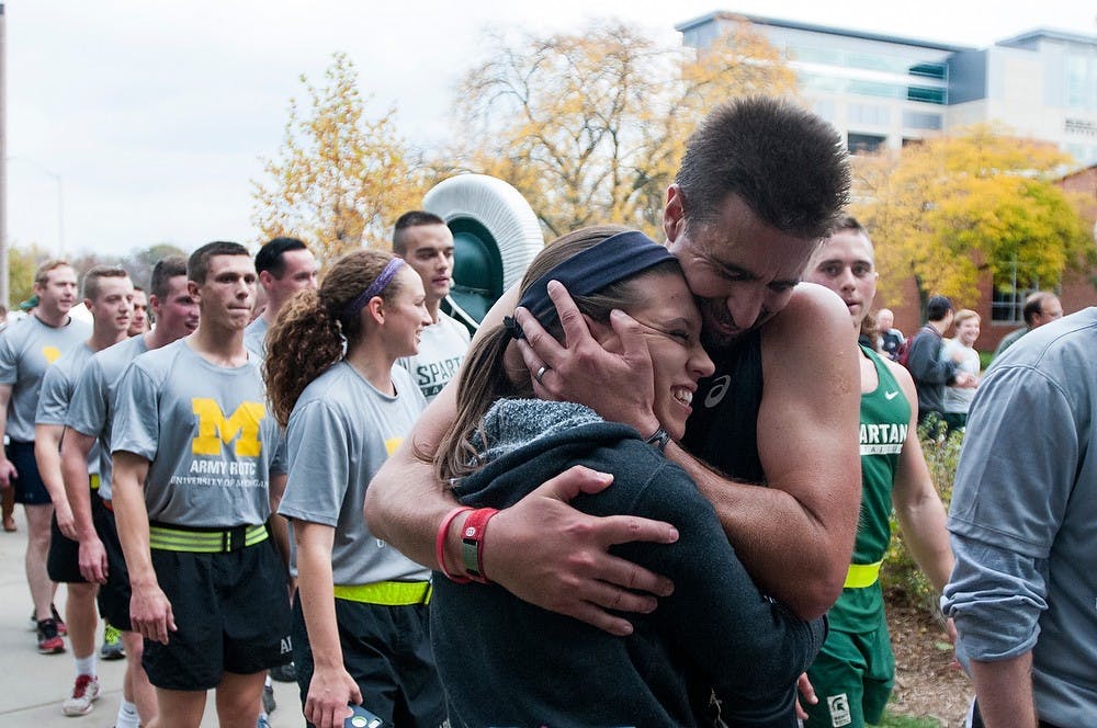 <p>Playmakers ultra-marathoner Michael Richmond clutches his daughter after the 11-hour, 64 mile run from Ann Arbor to East Lansing for Alex's Great State Race on Oct. 24, 2014, at Dem Hall. Dylan Vowell/The State News</p>