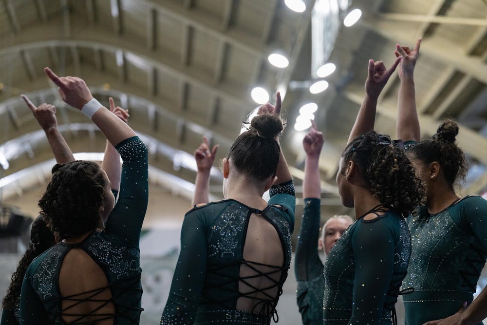 Michigan State gymnasts celebrate after their balance beam rotation during the MSU tri-meet at Jenison Field House on Sunday, Feb. 15, 2026.