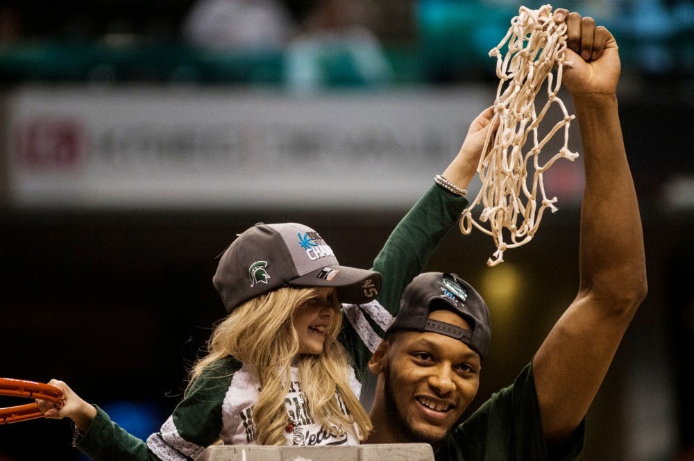 <p>Senior forward Adreian Payne holds up the net with St. Johns, Mich., resident Lacey Holsworth, 8, on March 16, 2014, after the game against Michigan at the Big Ten Championship at Bankers Life Fieldhouse in Indianapolis. The Spartans defeated the Wolverines, 69-55. Erin Hampton/The State News</p>