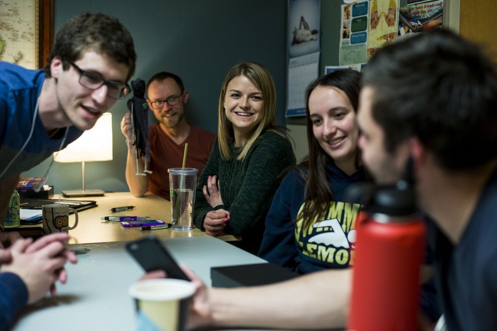 From left to right, neuroscience senior Noah Cohen, East Lansing resident Greg Dagner, graduate student Emily Young and economics senior Kim Gannon look at Ben's, who did not provide his last name, phone showing a photo of his niece during the MSU Traveler's Club meeting on March 31, 2017 at Olin Health Center. The MSU Traveler's Club is a club that provides a social space and support for people who are in recovery from addiction. 