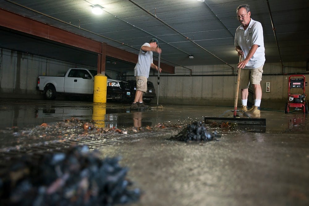 	<p>Larry Brown, a Community Resource Management Company maintenance employee, cleans a parking garage Aug. 28, 2013 beneath the apartments on 137 Louis St. The flooding caused damage to multiple cars in the parking structure. Julia Nagy/The State News </p>