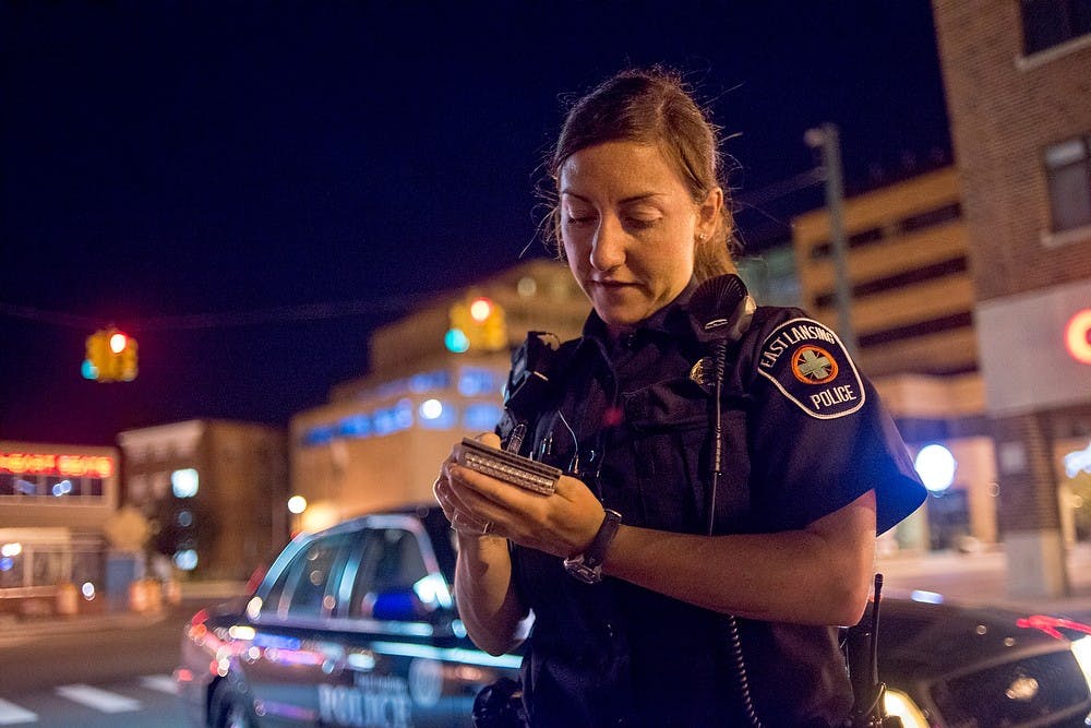 	<p>East Lansing police Officer Traci Sperry writes down contact information of witnesses of a crime on July 21, 2013, on M.A.C. Avenue. Sperry primarily works night shifts during the summer. Justin Wan/The State News</p>